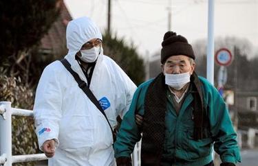 Un hombre con traje protector acompaa a un anciano mientras es evacuado a un refugio. | EFE